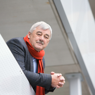 Man die buiten staat op gallerij van zijn woongebouw